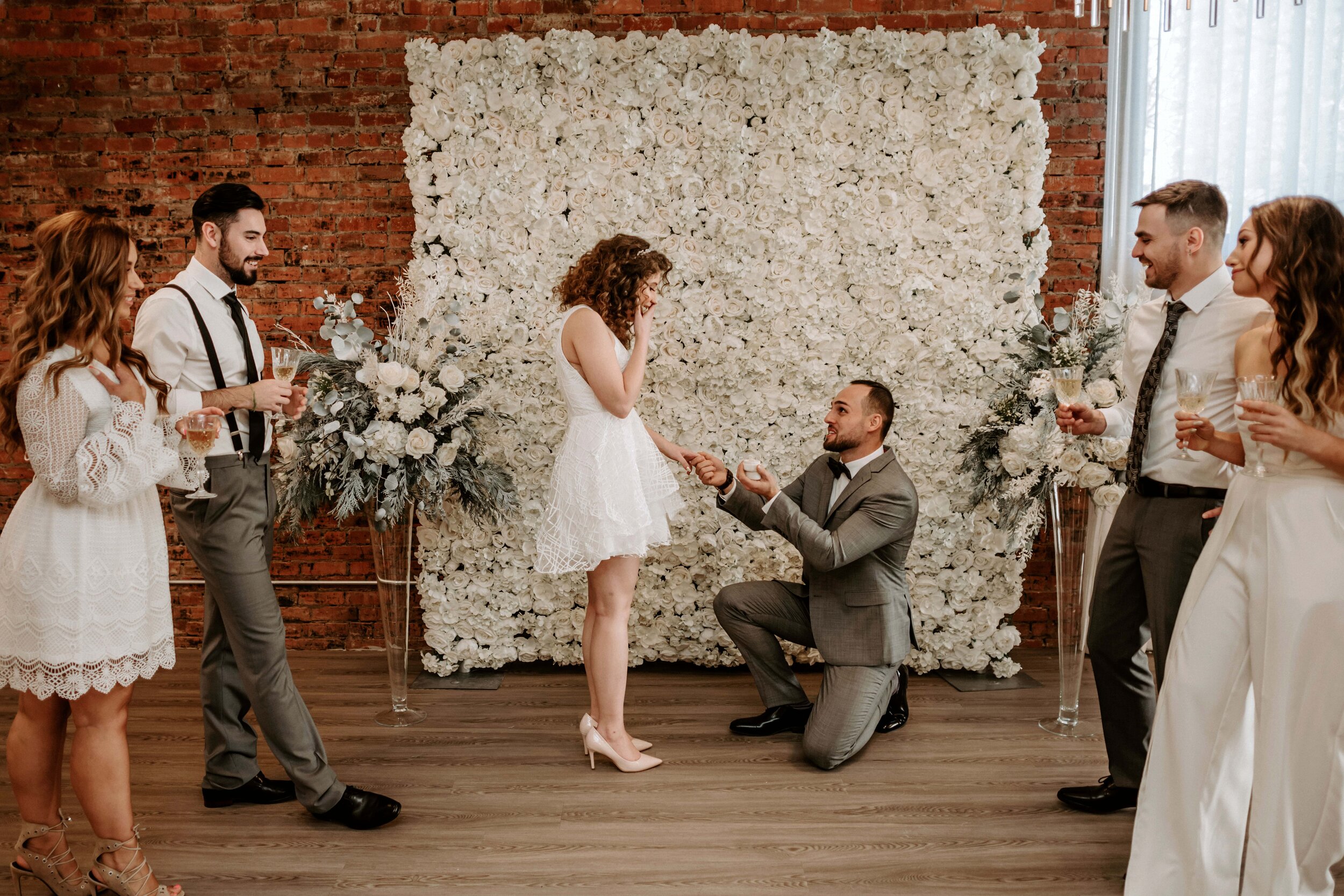  New Years eve surprise proposal in front of white flower wall 